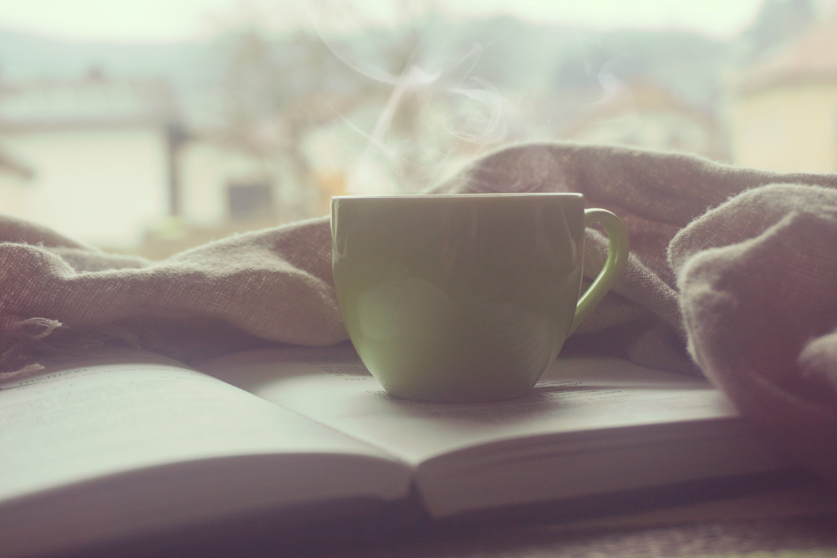 Tasse Tee auf einem offenem Buch – Symbol für Ruhe und Reflexion