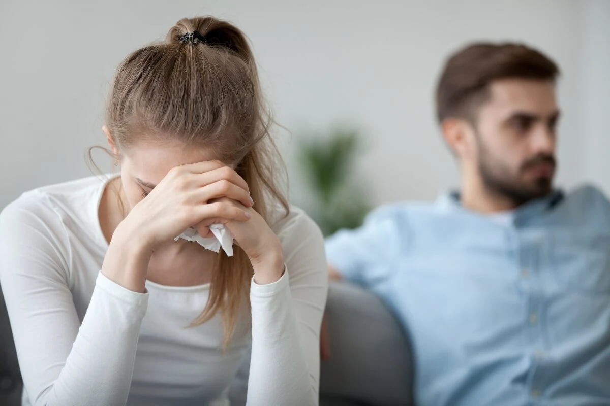 Wenn Erwartungen zwischen zwei Menschen stehen Traurige Frau sitzt mit einem Mann auf einem Sofa und beide wenden sich voneinander ab.