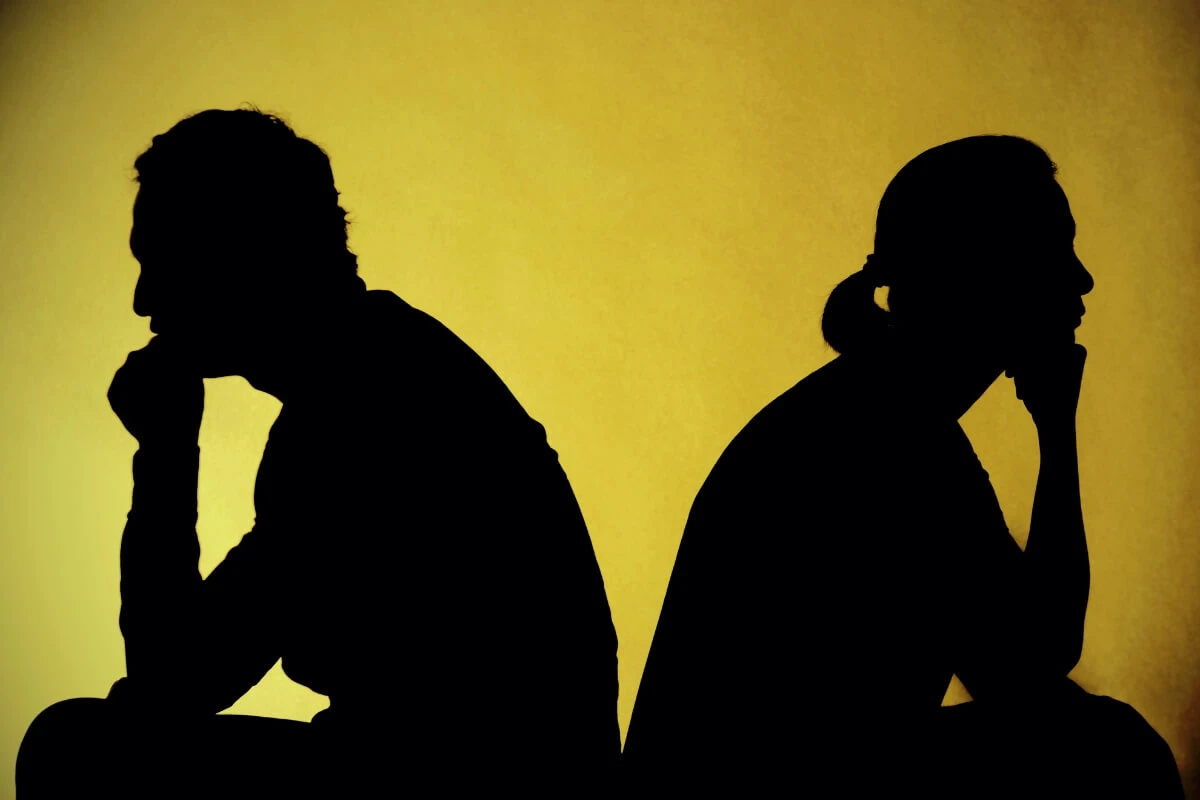 Unsichtbare Schutzmauern Zwei Menschen sitzen Rücken an Rücken und wirken emotional voneinander distanziert.